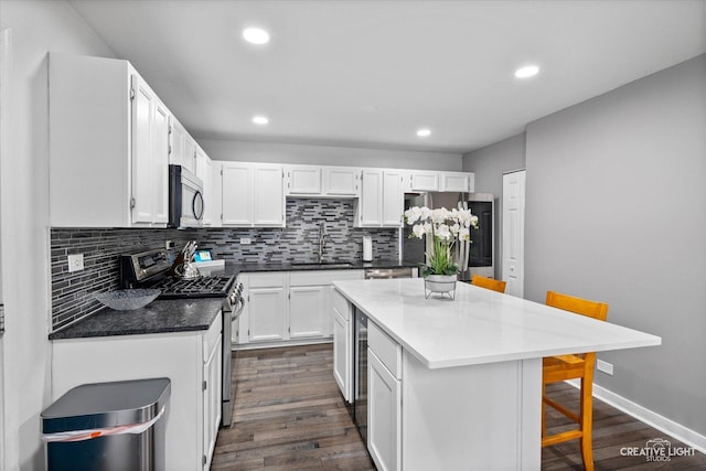 kitchen featuring backsplash, dark wood-style floors, a center island, white cabinetry, and stainless steel appliances