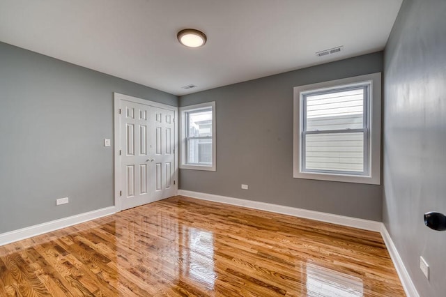 unfurnished bedroom featuring multiple windows, a closet, and light hardwood / wood-style flooring