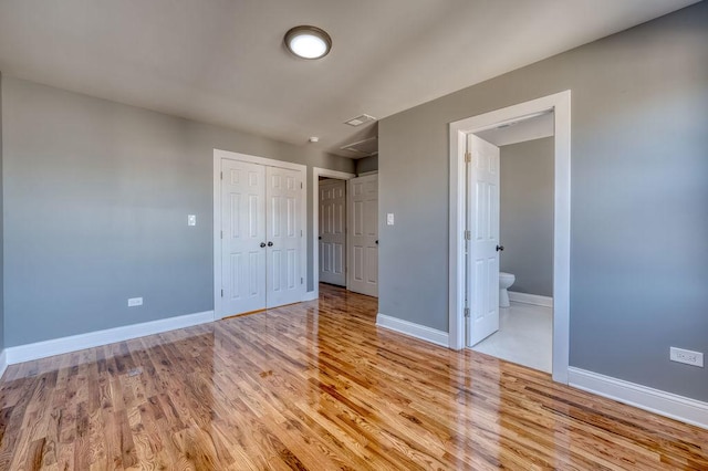 unfurnished bedroom featuring ensuite bathroom, light hardwood / wood-style floors, and a closet