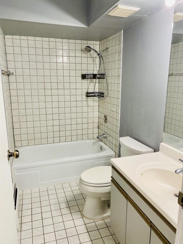 full bathroom featuring tile patterned flooring, vanity, tiled shower / bath combo, and toilet