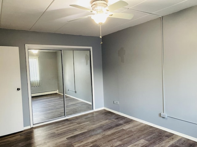 unfurnished bedroom featuring dark wood-type flooring, a baseboard radiator, ceiling fan, and a closet