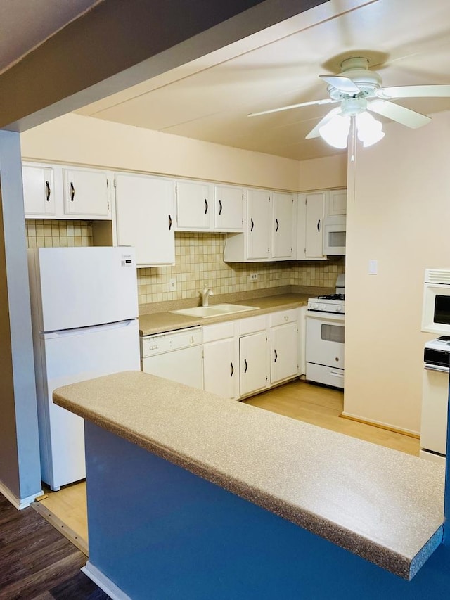 kitchen with sink, white appliances, white cabinets, and backsplash