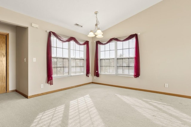 carpeted empty room featuring lofted ceiling and a chandelier