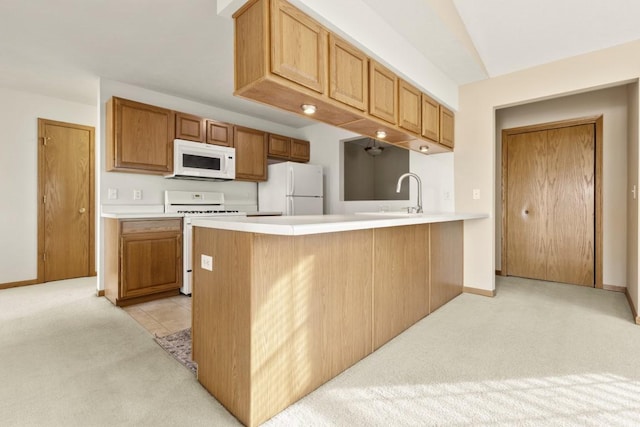 kitchen with white appliances, kitchen peninsula, sink, and light carpet