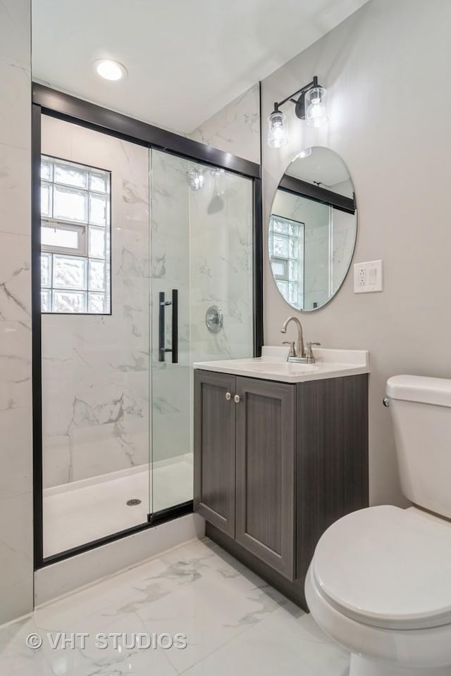 bathroom featuring vanity, toilet, and a shower with shower door