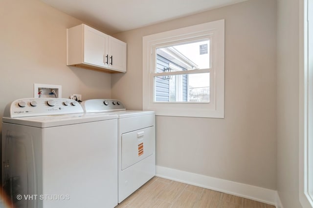 laundry room with light hardwood / wood-style floors, washing machine and dryer, and cabinets