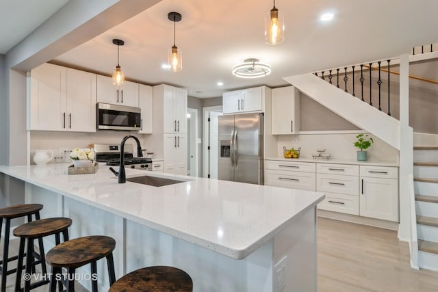 kitchen with a breakfast bar, appliances with stainless steel finishes, white cabinetry, decorative light fixtures, and kitchen peninsula