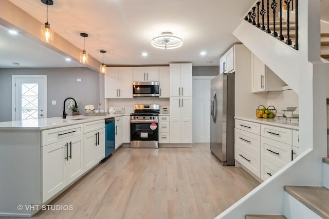 kitchen featuring sink, white cabinetry, decorative light fixtures, appliances with stainless steel finishes, and kitchen peninsula