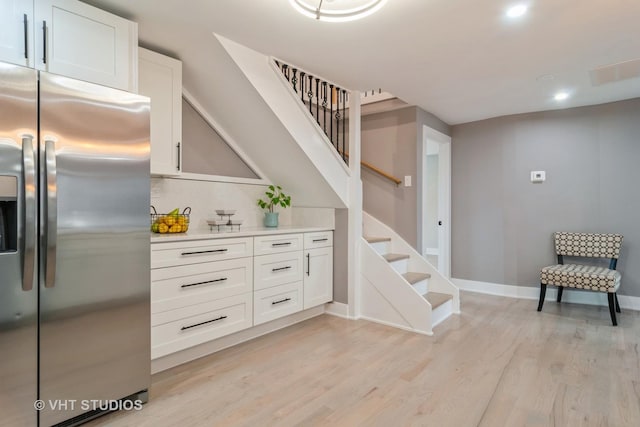 interior space with white cabinetry, light hardwood / wood-style floors, and stainless steel fridge with ice dispenser