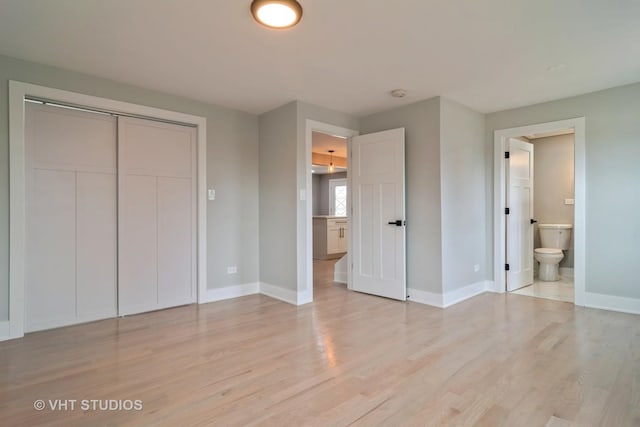 unfurnished bedroom featuring ensuite bathroom, light hardwood / wood-style floors, and a closet