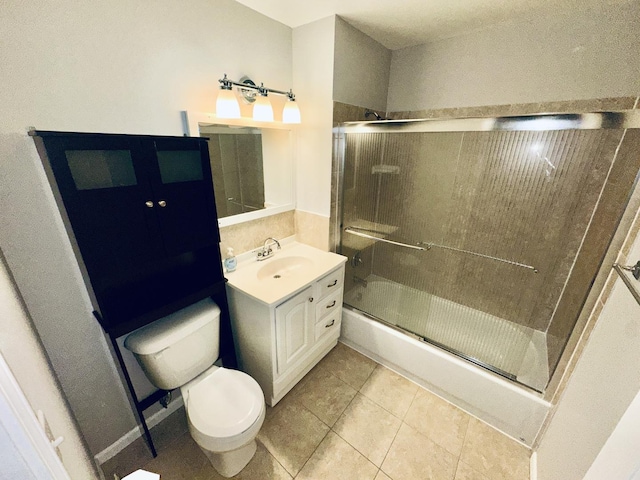 full bathroom with bath / shower combo with glass door, vanity, tile patterned floors, and toilet