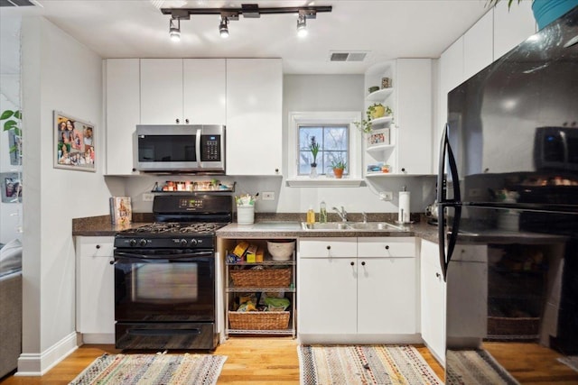 kitchen with white cabinetry, sink, light hardwood / wood-style flooring, and black appliances