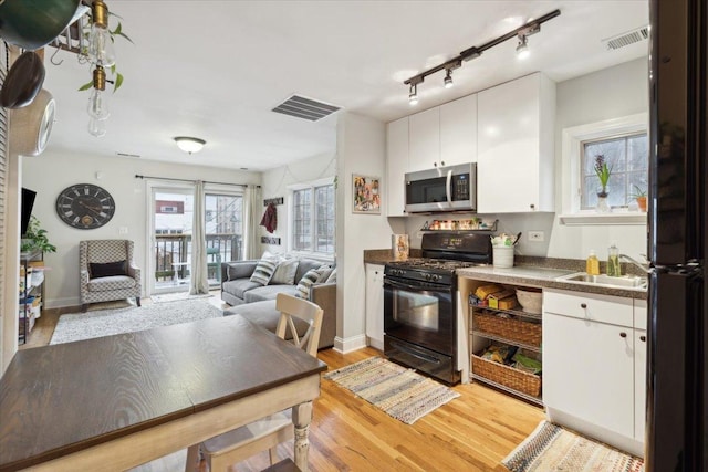 kitchen featuring white cabinetry, sink, light wood-type flooring, and black appliances