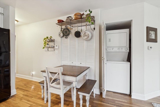 dining area featuring stacked washer / dryer and light hardwood / wood-style flooring