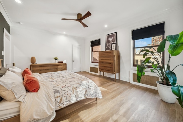 bedroom featuring multiple windows, crown molding, light hardwood / wood-style floors, and ceiling fan