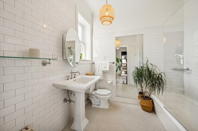 bathroom with a tub to relax in, toilet, tile patterned flooring, and tile walls