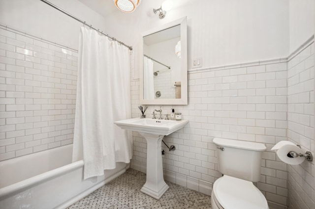 bathroom featuring tile walls, toilet, and shower / bath combo with shower curtain