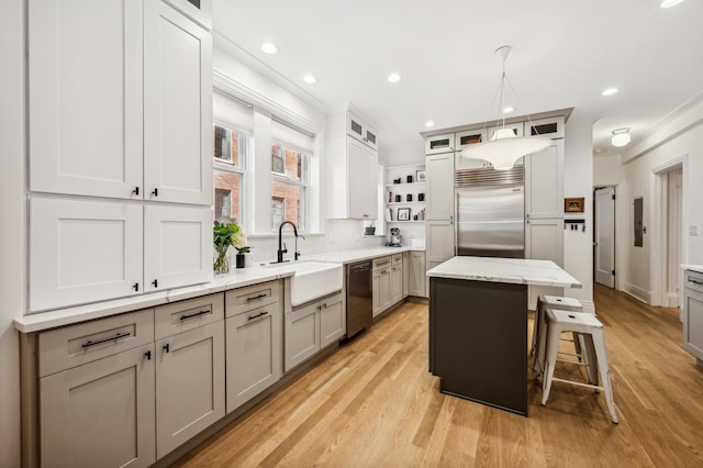 kitchen with a kitchen island, sink, gray cabinetry, a kitchen bar, and stainless steel appliances