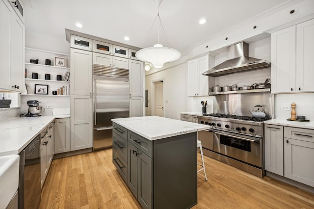 kitchen featuring wall chimney range hood, gray cabinets, hanging light fixtures, a center island, and high quality appliances