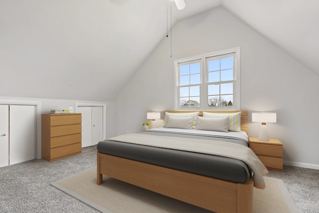 bedroom featuring vaulted ceiling, two closets, and light carpet