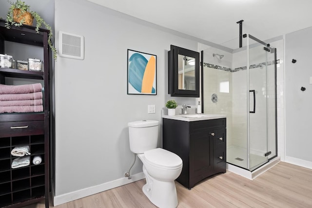 bathroom with wood-type flooring, walk in shower, vanity, and toilet