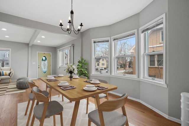 dining room featuring a notable chandelier, beam ceiling, and light hardwood / wood-style floors