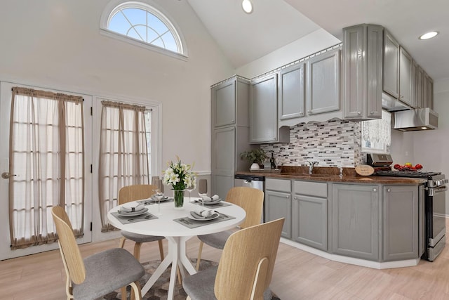 kitchen with gas range, backsplash, high vaulted ceiling, and gray cabinetry