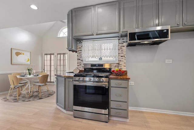 kitchen with tasteful backsplash, lofted ceiling, stainless steel appliances, and gray cabinets