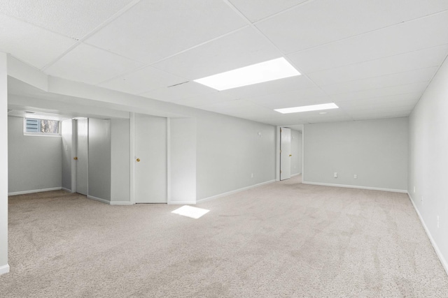 basement featuring a drop ceiling and light carpet