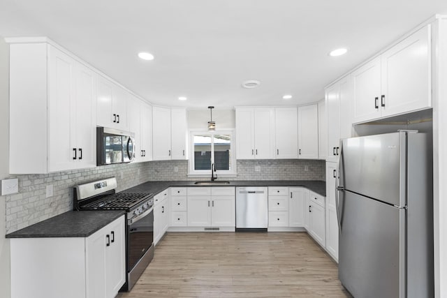 kitchen featuring white cabinetry, sink, backsplash, stainless steel appliances, and light wood-type flooring