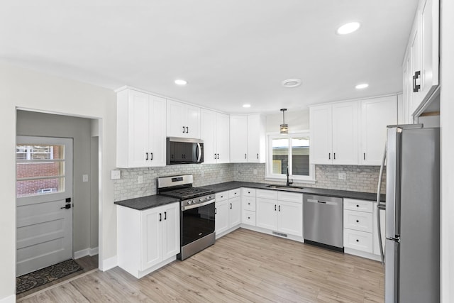 kitchen with sink, light hardwood / wood-style flooring, pendant lighting, stainless steel appliances, and white cabinets