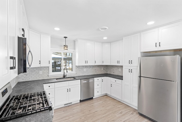 kitchen featuring white cabinetry, appliances with stainless steel finishes, sink, and pendant lighting