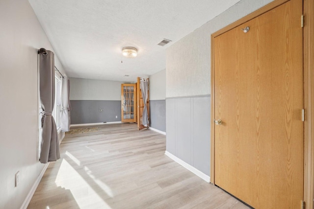 hallway featuring light hardwood / wood-style flooring and a textured ceiling