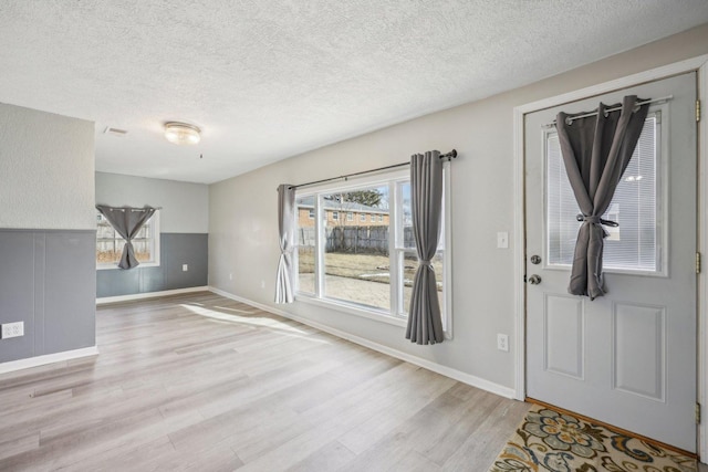 foyer with a healthy amount of sunlight, light hardwood / wood-style flooring, and a textured ceiling