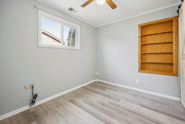 spare room featuring crown molding, light hardwood / wood-style flooring, a barn door, and ceiling fan