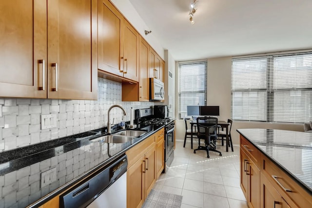 kitchen featuring light tile patterned flooring, sink, tasteful backsplash, appliances with stainless steel finishes, and dark stone counters