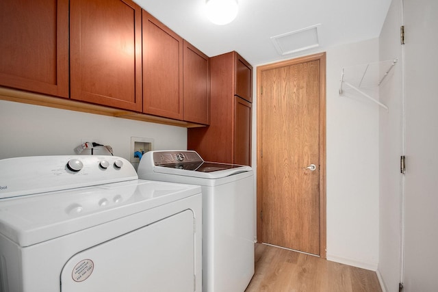 clothes washing area featuring cabinets, washing machine and dryer, and light hardwood / wood-style flooring