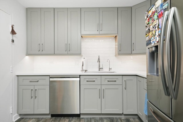 kitchen featuring sink, appliances with stainless steel finishes, dark hardwood / wood-style floors, gray cabinets, and backsplash