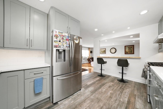 kitchen featuring tasteful backsplash, stainless steel appliances, hardwood / wood-style floors, and gray cabinetry