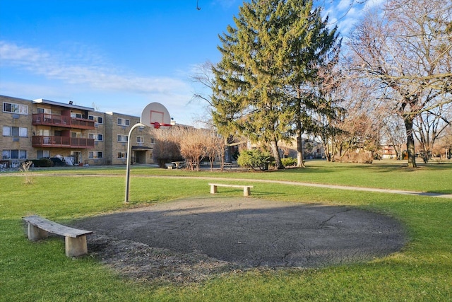 view of property's community featuring basketball court and a yard