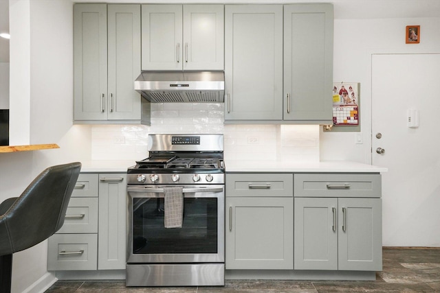 kitchen featuring gas stove, gray cabinetry, ventilation hood, dark hardwood / wood-style floors, and backsplash