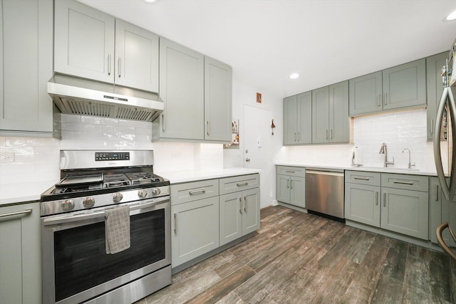 kitchen featuring sink, backsplash, dark wood-type flooring, and appliances with stainless steel finishes