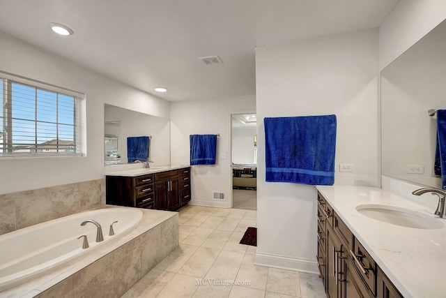 bathroom featuring vanity, tiled tub, and tile patterned flooring