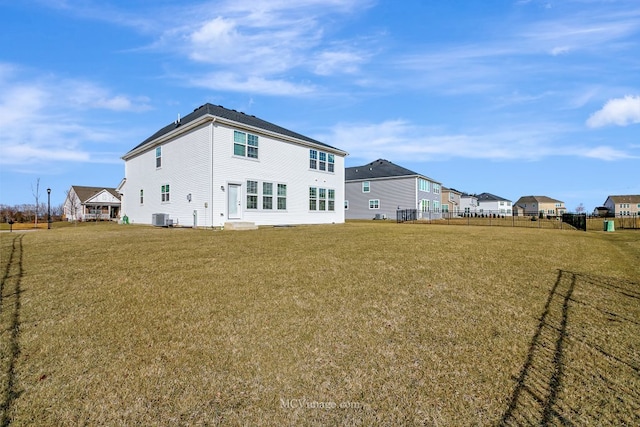 rear view of property with central AC and a lawn