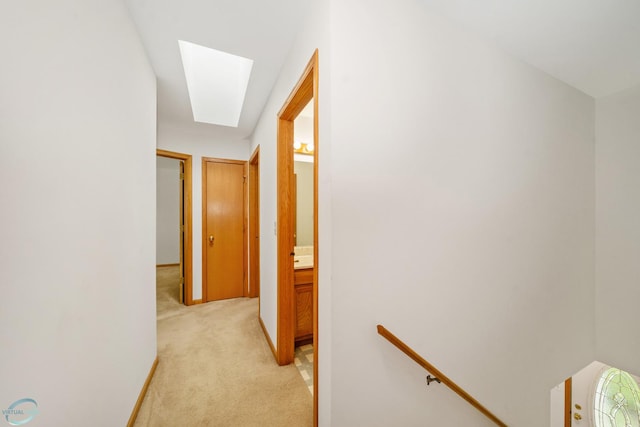 hallway featuring a skylight and light colored carpet