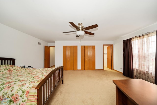 bedroom with multiple closets, ceiling fan, and light carpet