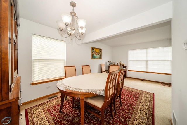 dining space featuring light colored carpet and a chandelier