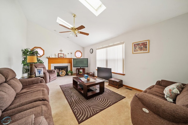 carpeted living room with a fireplace, a skylight, high vaulted ceiling, and ceiling fan