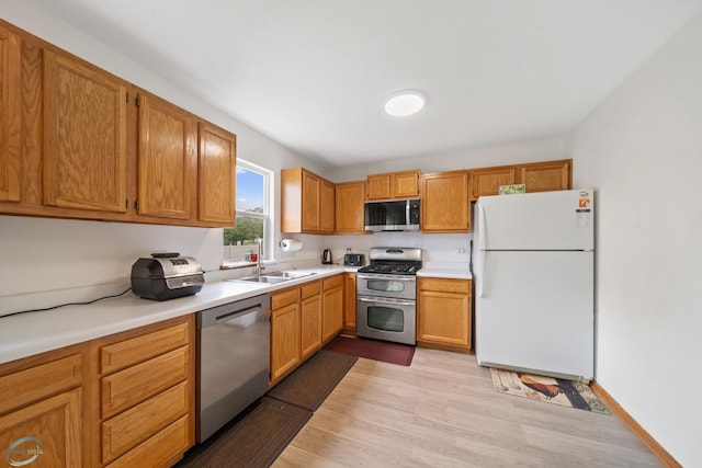 kitchen with appliances with stainless steel finishes, sink, and light wood-type flooring