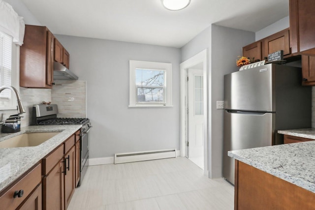 kitchen with appliances with stainless steel finishes, tasteful backsplash, a baseboard radiator, sink, and light stone countertops